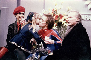 Harris (far left) sitting in the 1984 Olympic Kiss & Cry with Scott Hamilton & coach Don Laws.